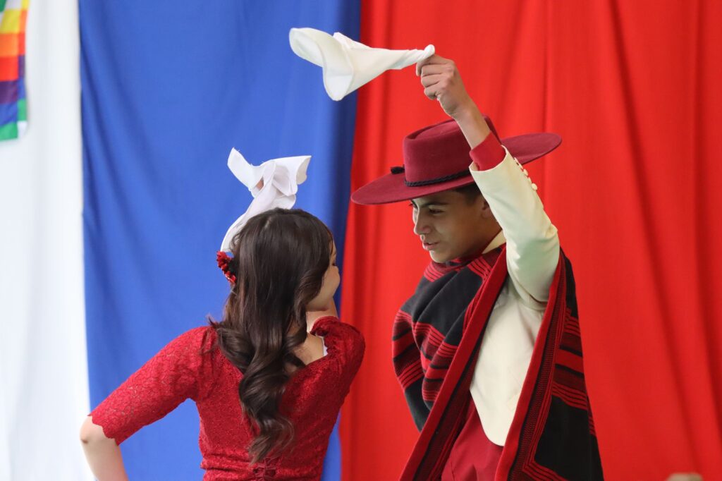 Estudiantes del Colegio Licancabur de Calama presentando bailes folclóricos durante la gala de fiestas patrias en Chile con trajes típicos coloridos